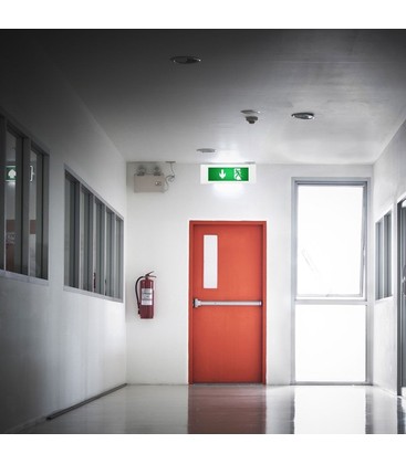 En installerad nödbelysningsarmatur i en modern korridormiljö som visar diskret väggmontering.