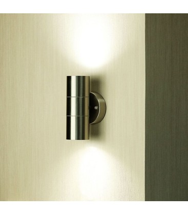 Modern vägglampa monterad på en husfasad som sprider ljus uppåt och nedåt.